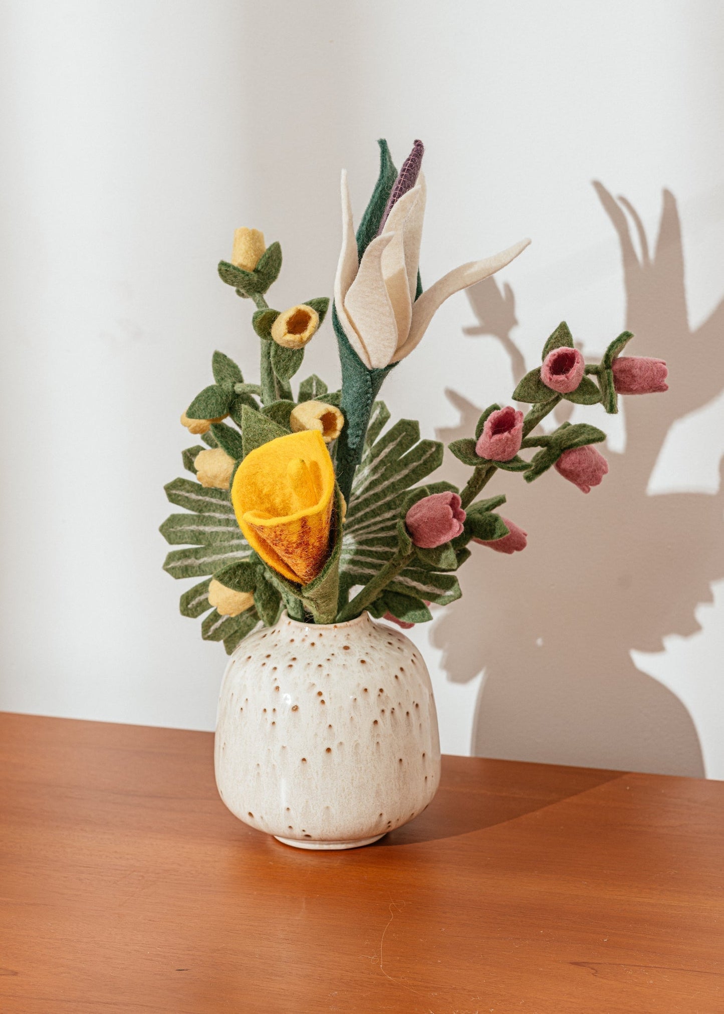 Pink and yellow Bellflowers in a white vase with other felt flowers.
