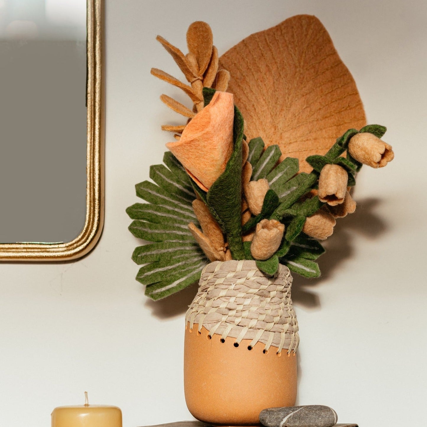 Pink felt Calla Lily flower in brown and white vase with tropical leaves.