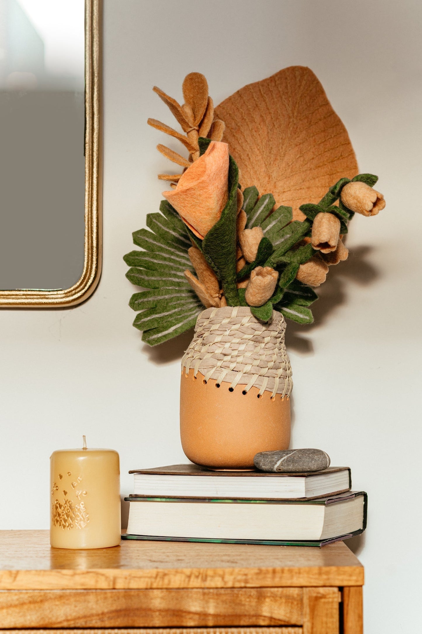 Pink felt Calla Lily flower in brown and white vase with tropical leaves.