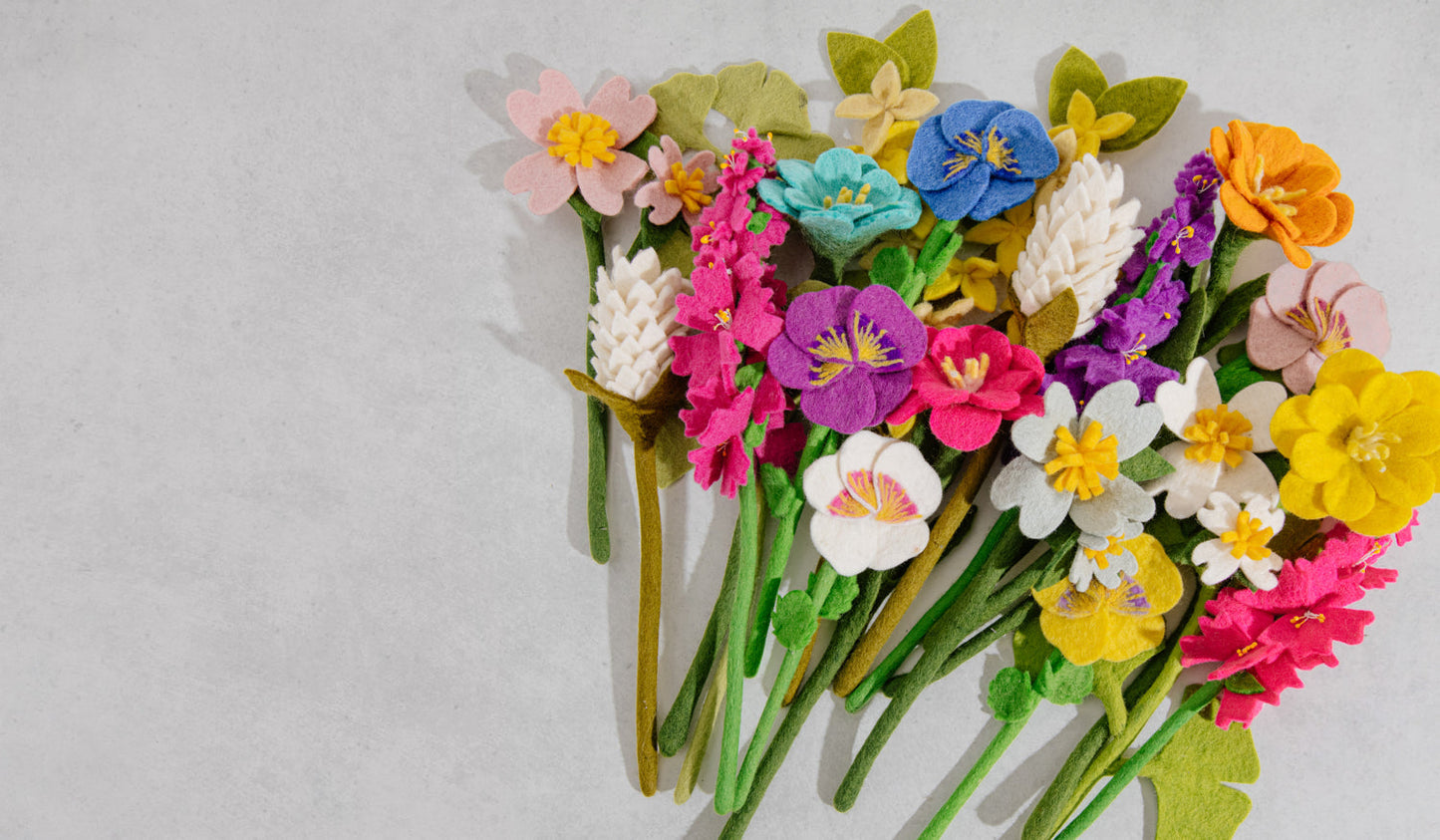 Bunch of multicolor felt flowers including Camellia flowers and daffodils.