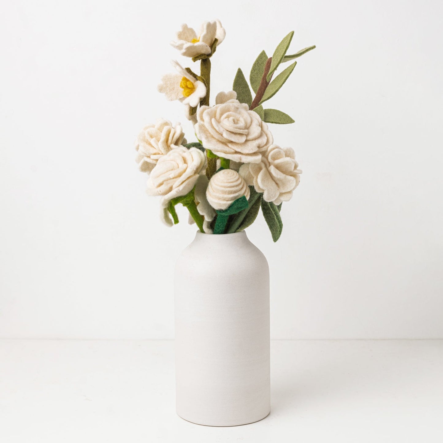 White and green felt floral arrangement in a white vase.