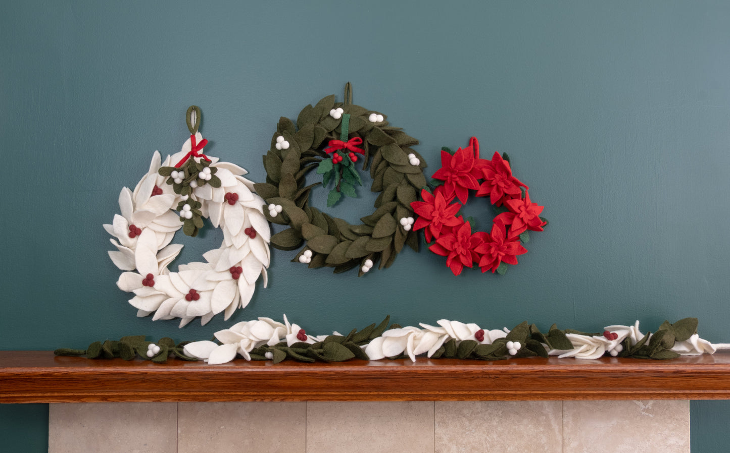 Felt ornament of Holly with berries and a red bow hanging with various wreaths.
