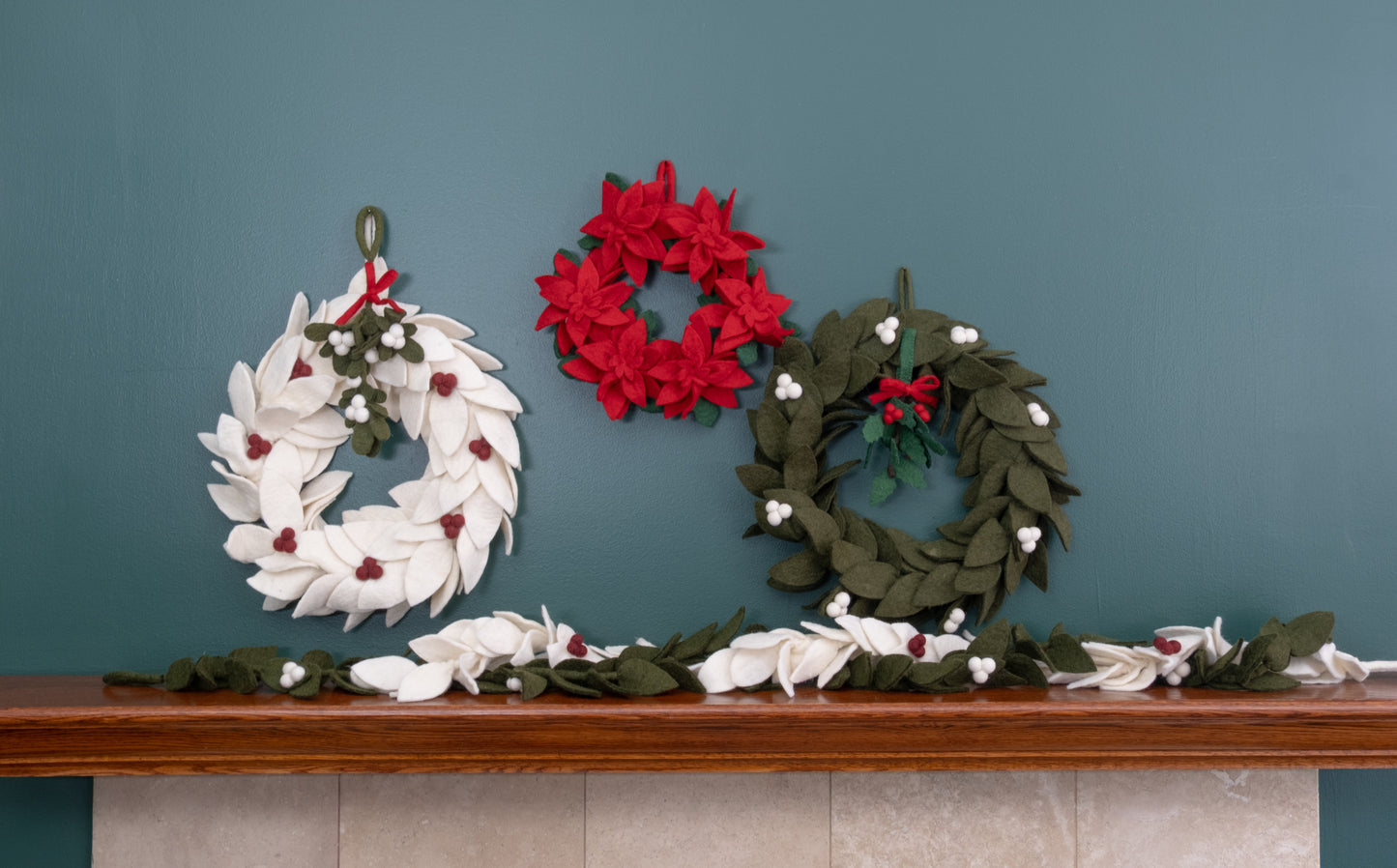Felt ornament of Holly with berries and a red bow hanging with various wreaths.