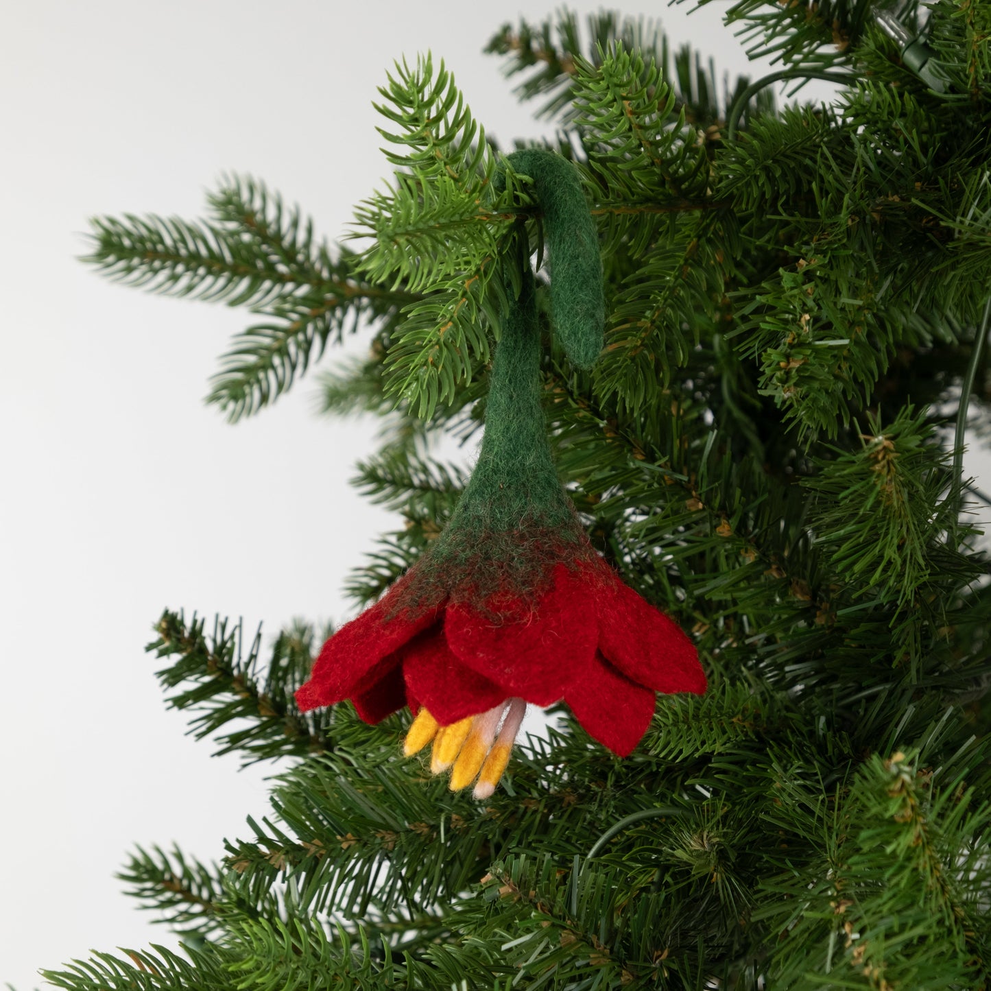 Felt ornament of a red flower on a Christmas tree.
