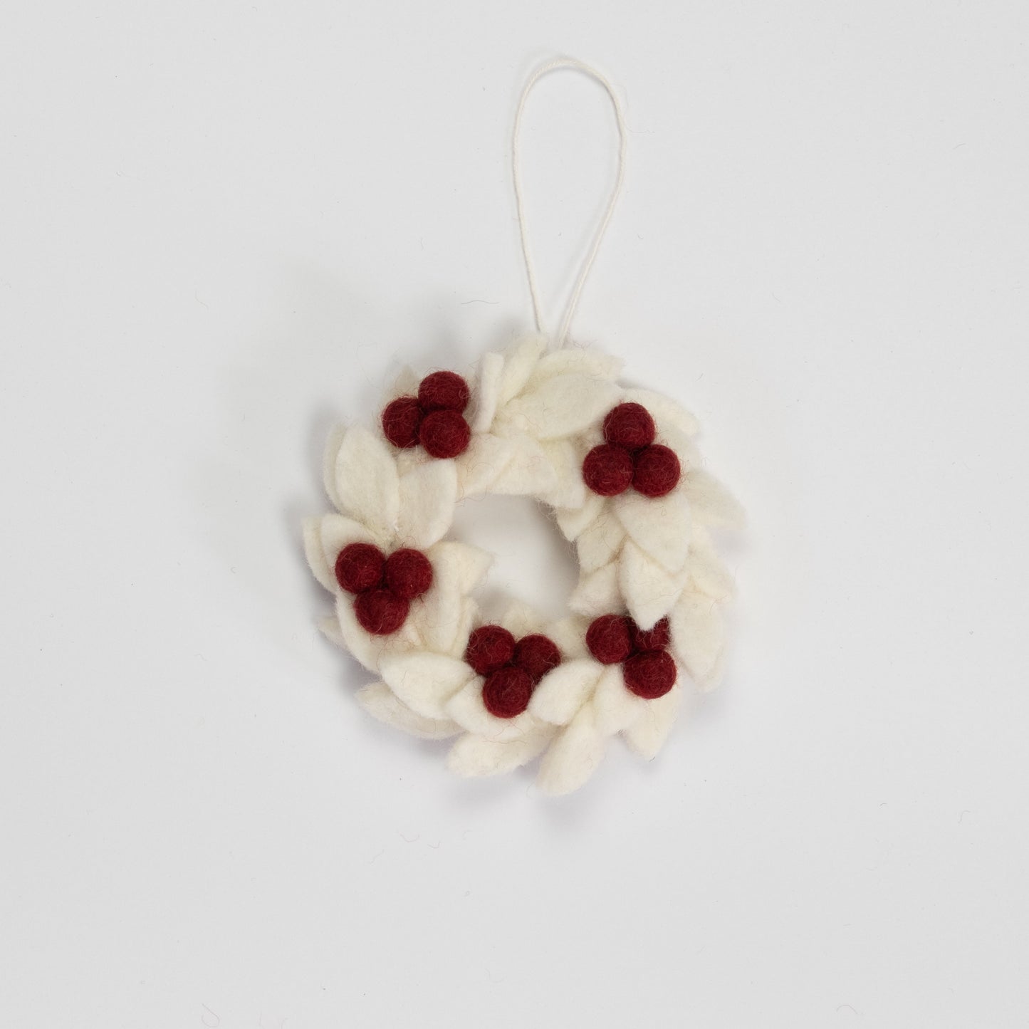 Felt ornament of a mini wreath in white with red berries.