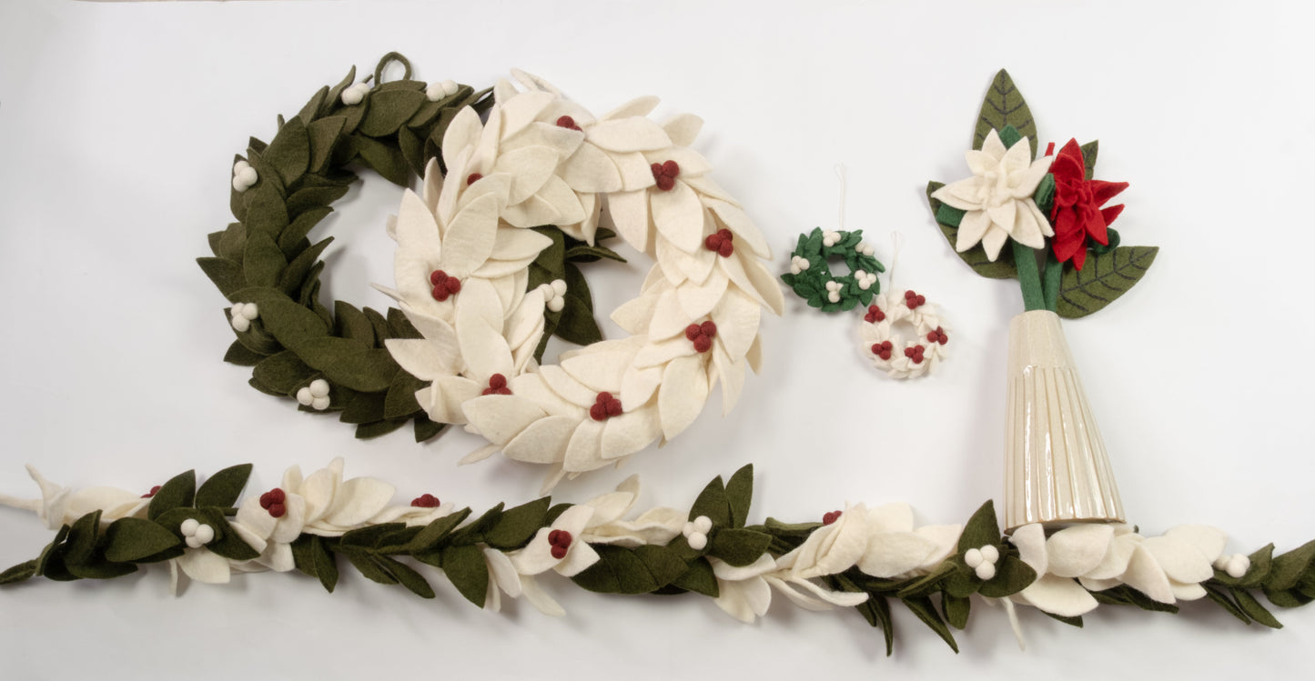 Various felt green, red and white wreaths, flowers, and garlands laid out.