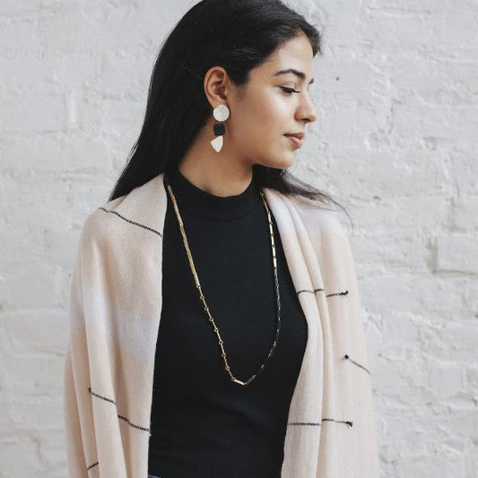 White, gold, and black link necklace on a woman with dark hair turned to the side.