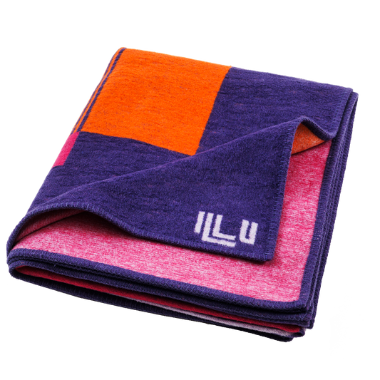 Blanket in bright purple, pink, and orange asymmetrical designs, folded into a square.