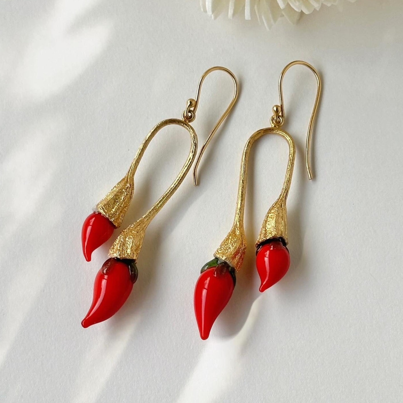 Pair of red and gold double chili pod earrings with silver colored findings.