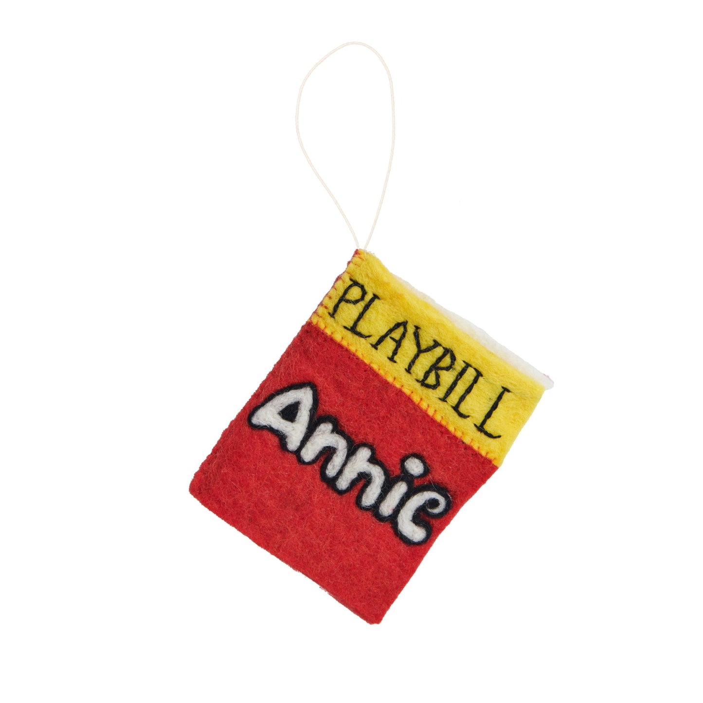 Felt ornament of a playbill for the Broadway play Annie showing Annie written in white with a red background.