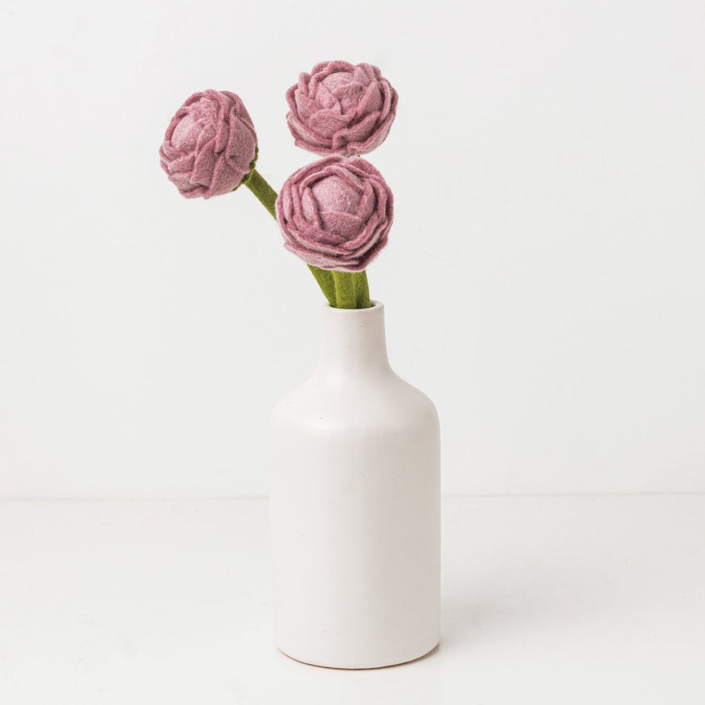 Pink and green felt floral arrangement in a white vase.