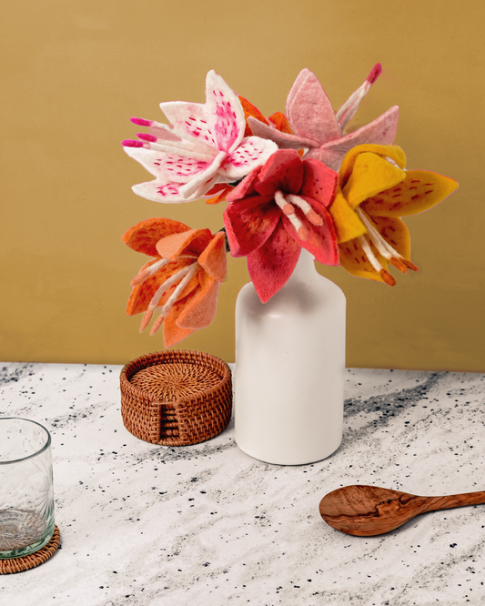 Bunch of felt Stargazer Lily flowers in orange, pink, yellow, peach, apricot, and white in a white vase.