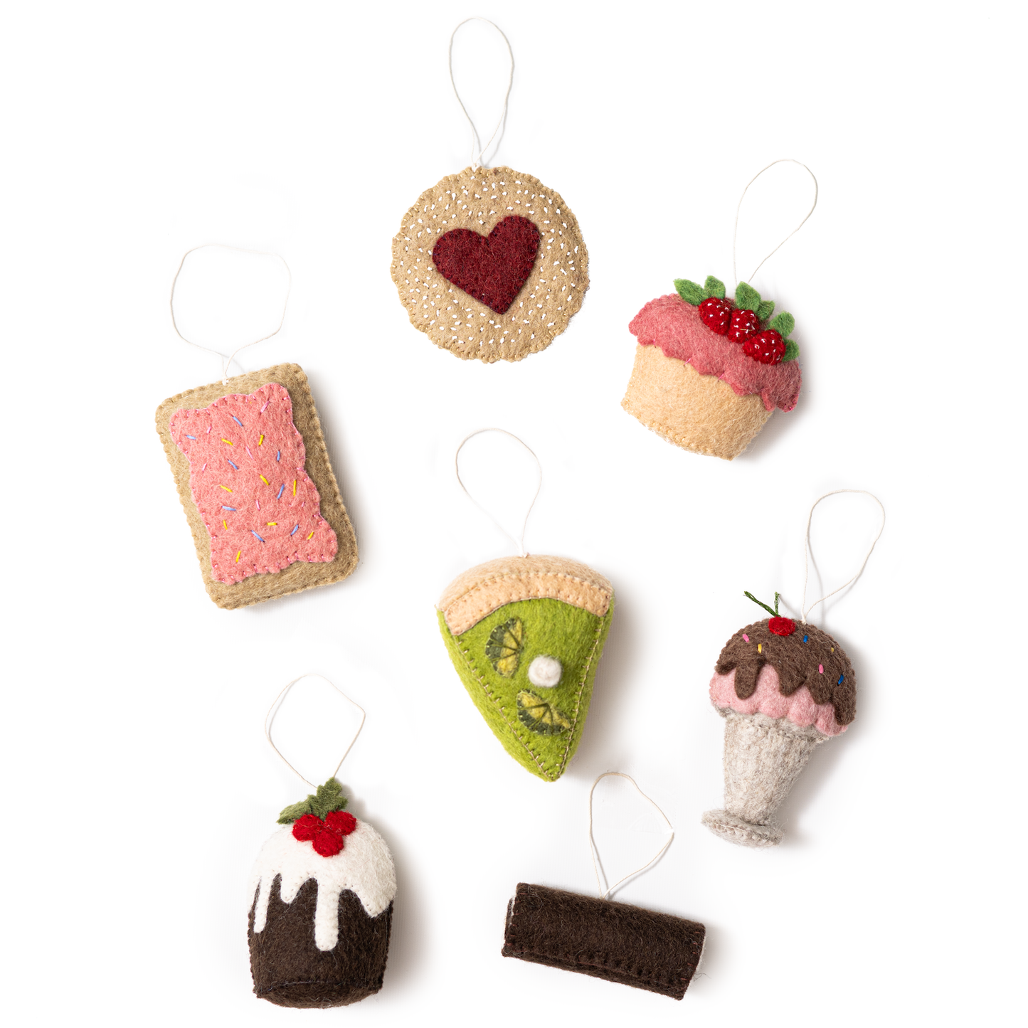 Scattered felt food ornaments of a pink pop tart, a Linzer cookie, a strawberry shortcake, key lime pie, ice cream sundae, Christmas pudding, and a Swiss roll cake.