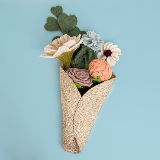 Brown woven wall vase with flowers on blue background.