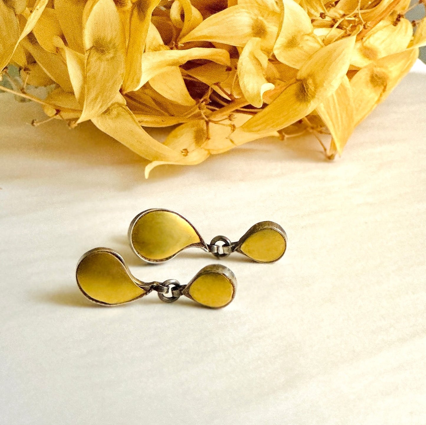Pair of gold foil earrings with tribal design. Gold petals at top of image.