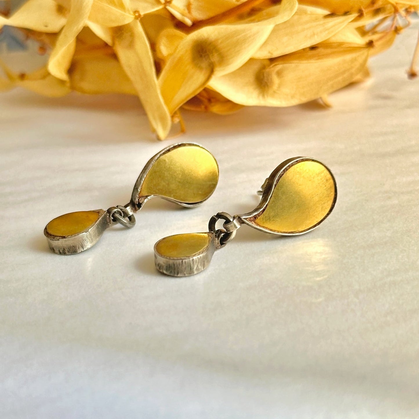 Pair of gold foil earrings with tribal design. Gold petals at top of image.