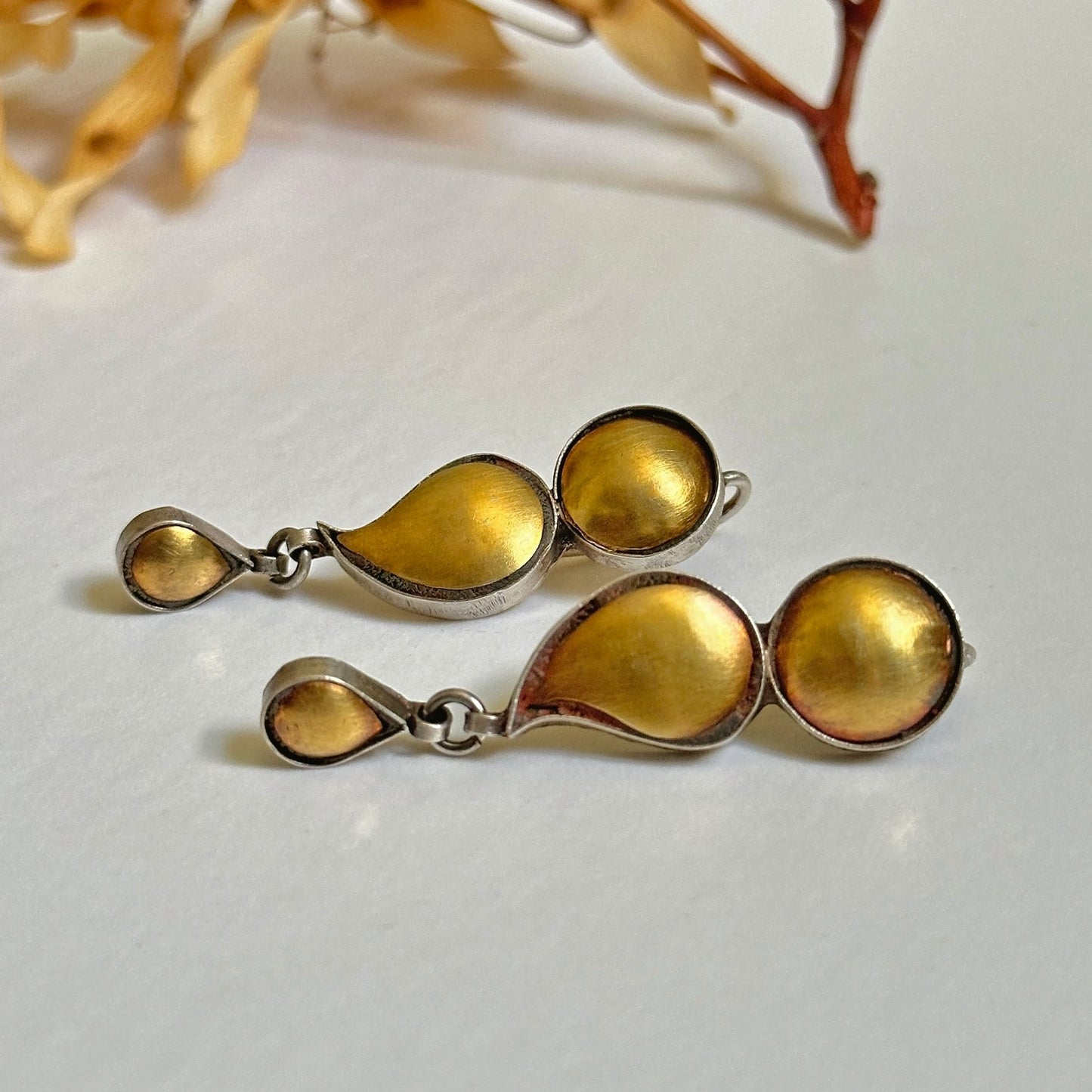Pair of gold foil earrings with tribal design, laying on side.