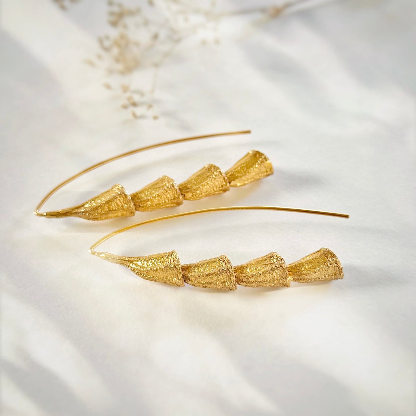 Pair of gold plated dangle earrings laying on side.
