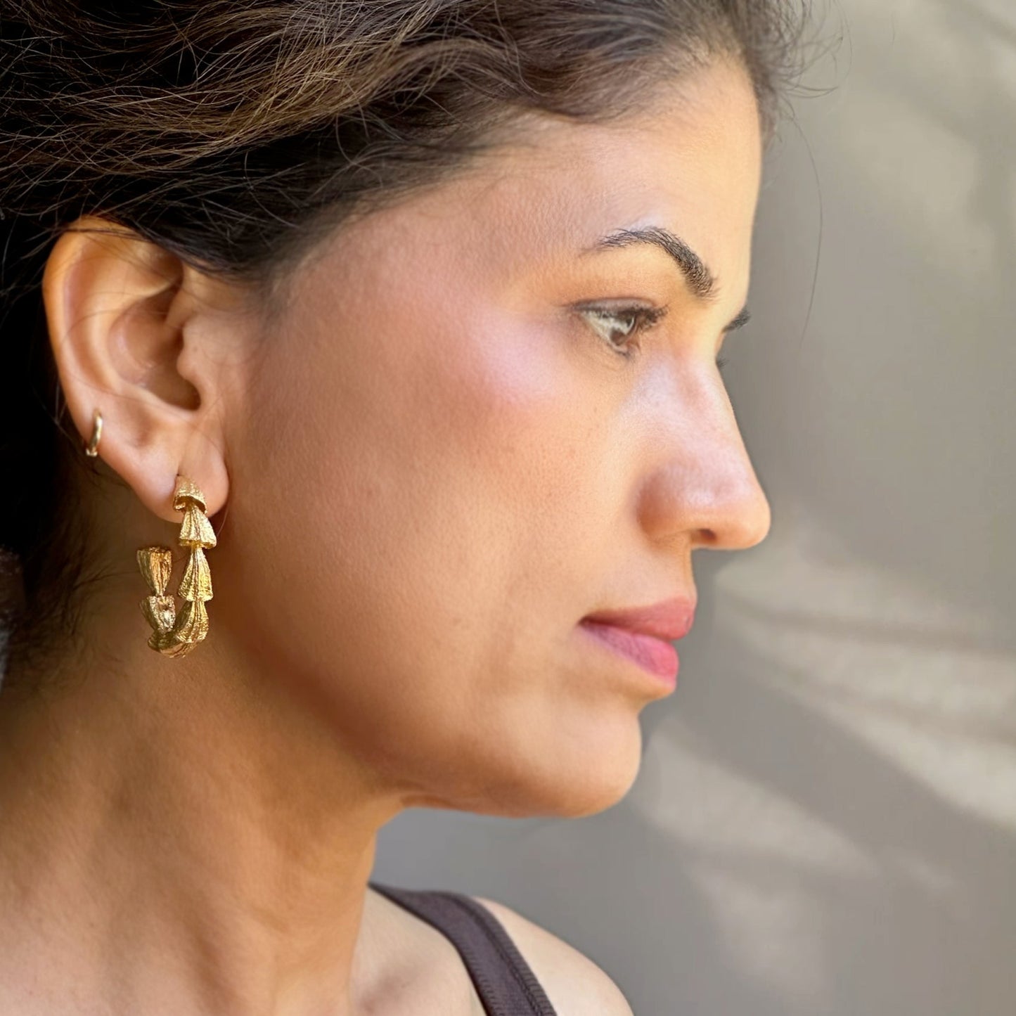 Right front view of woman wearing gold hoop earrings.
