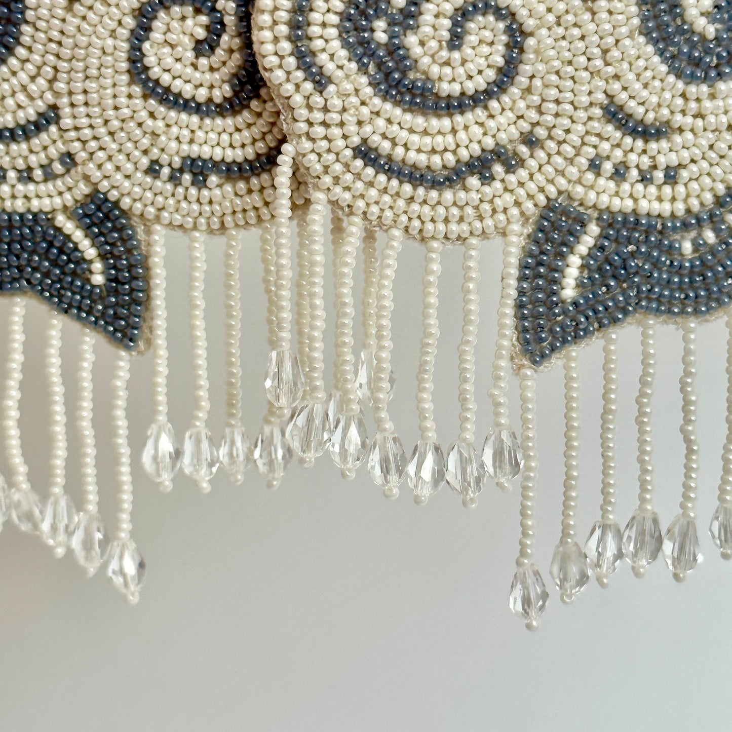 Closeup of white and black cloud earrings with tassels.