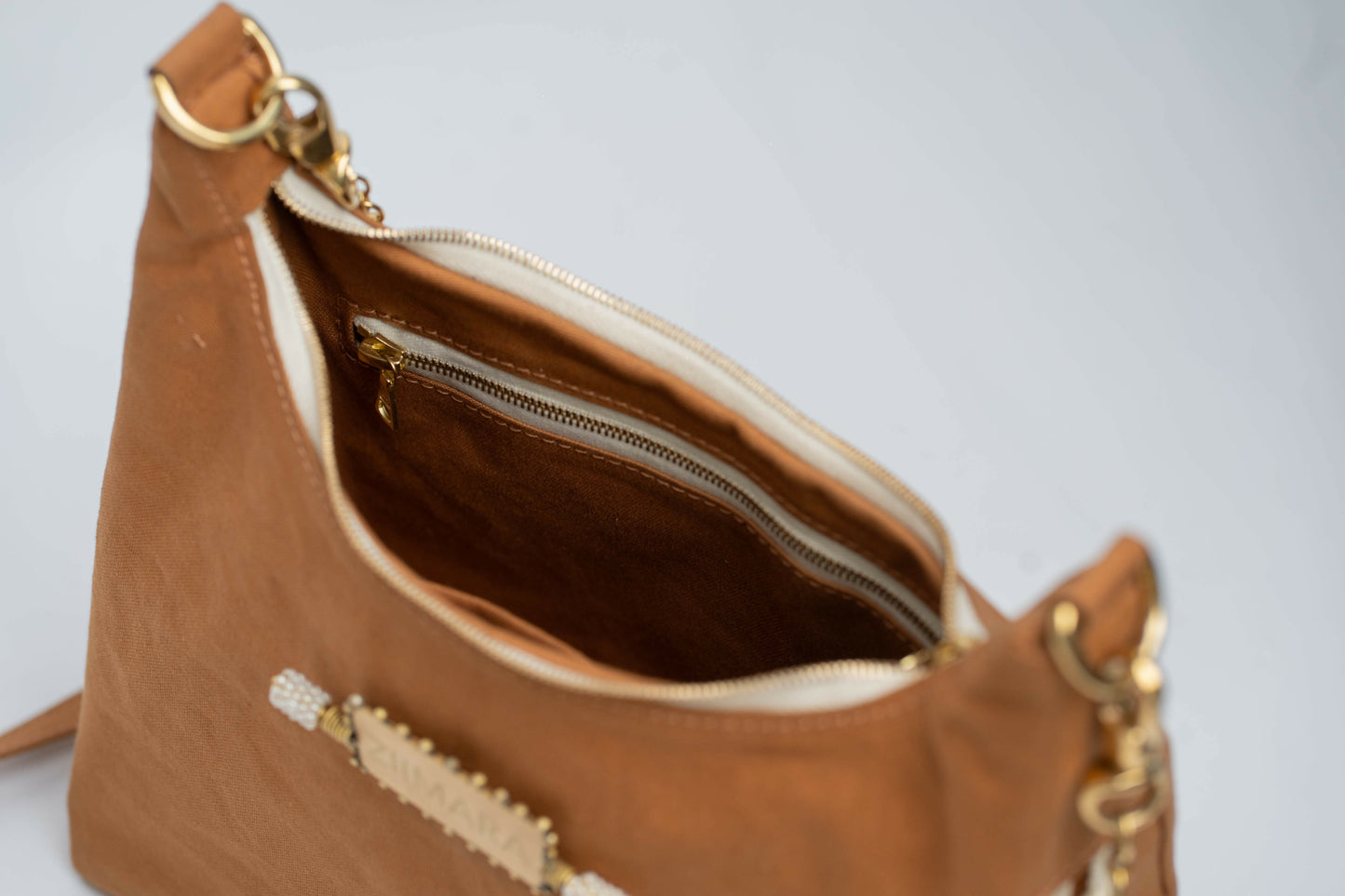 Top front view looking into brown handbag with gold colored top zipper.