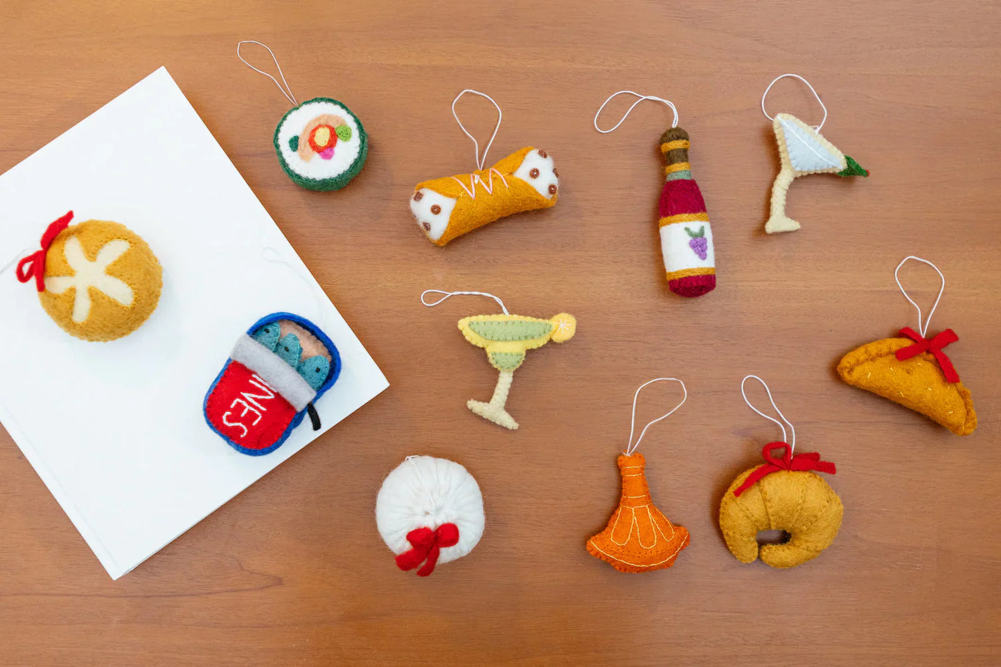 Scattered felt ornaments of various food shapes like sushi, cocktails, a taco etc.
