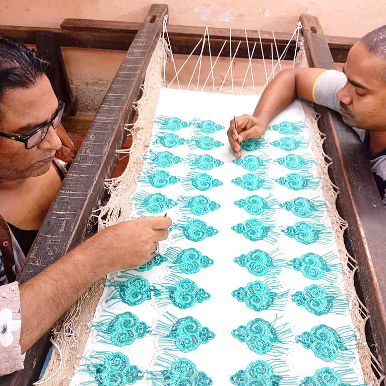 Artisans making light and dark green cloud earrings with tassels.