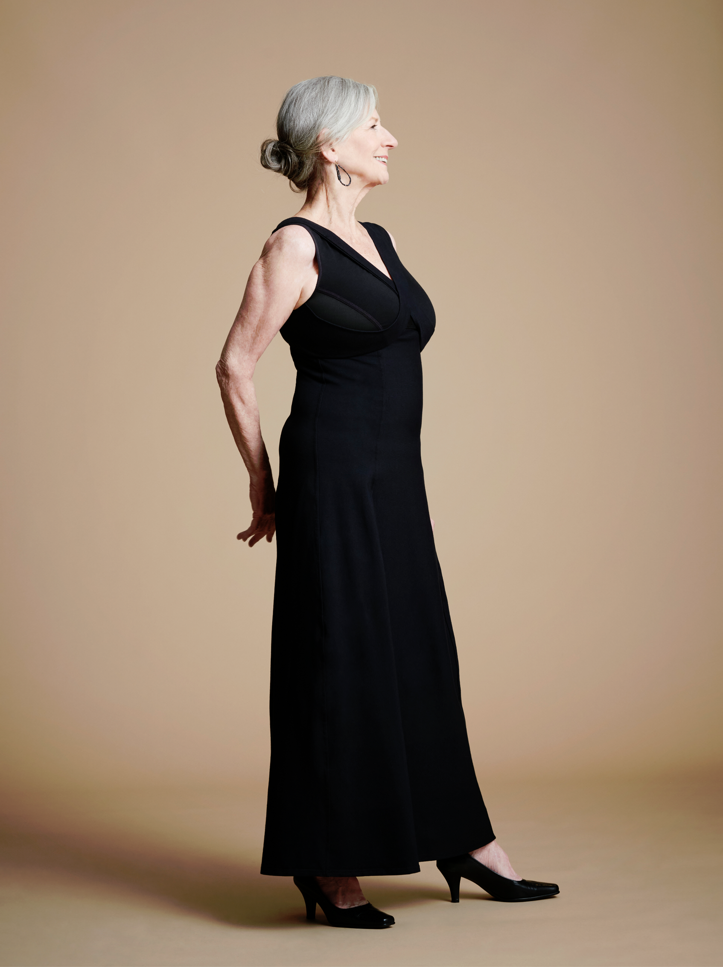 Front right view of woman wearing long black dress with lay-flat v neck look.