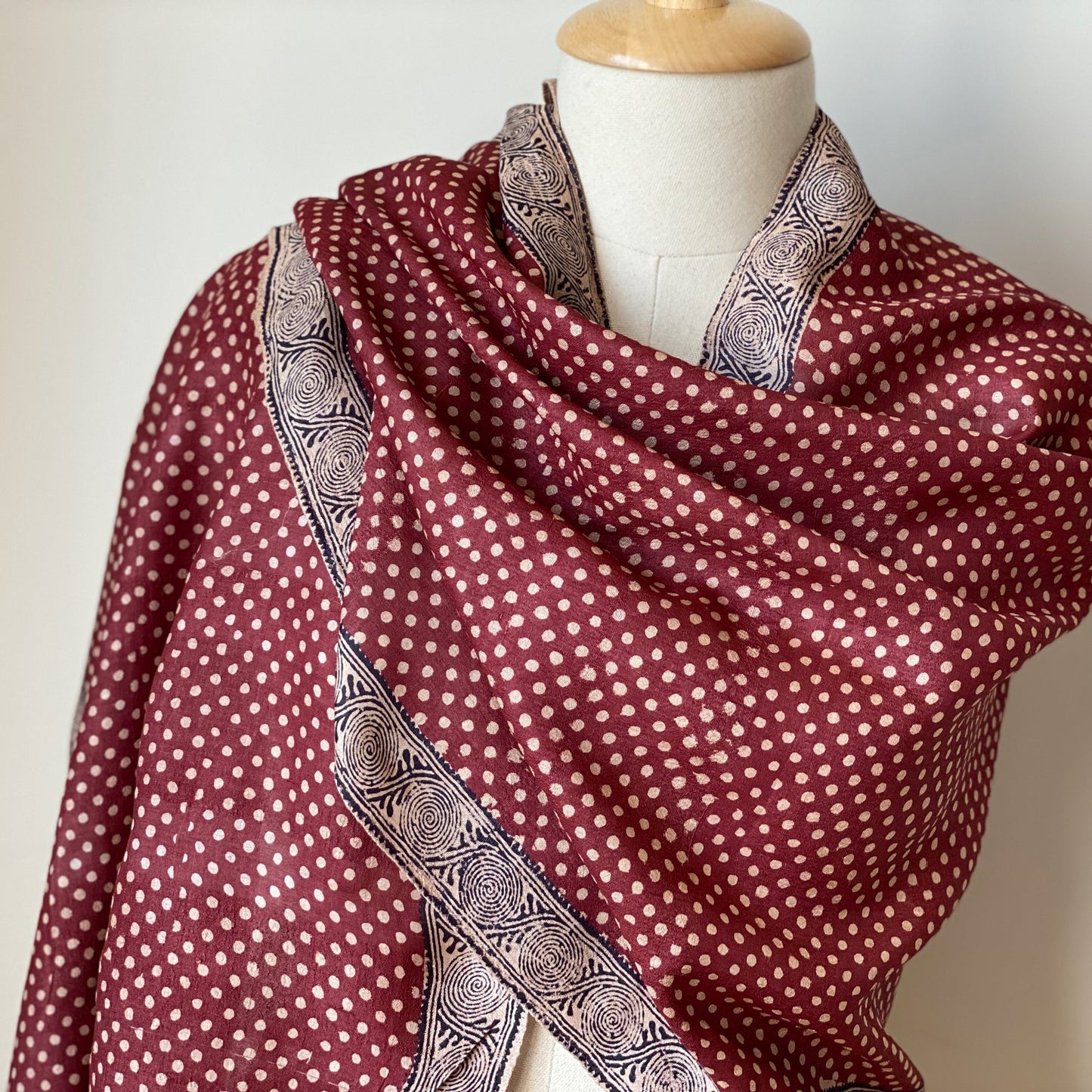 Manikin wrapped in red, natural, black stole with natural polka dots.