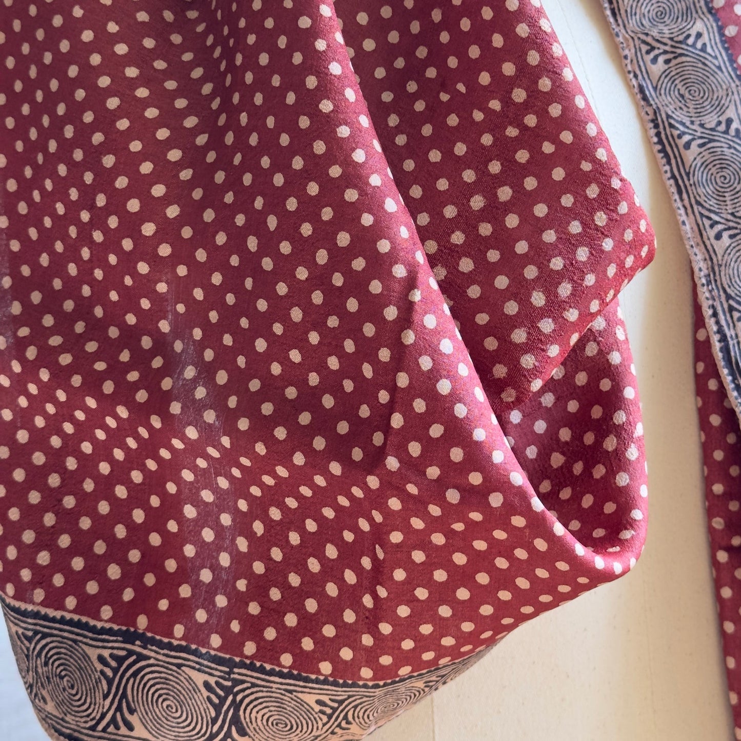 Closeup of red with natural polka dots scarf with black and natural trim.
