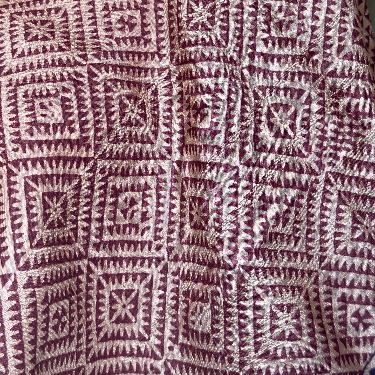 Closeup of red and natural colored scarf with square pattern.