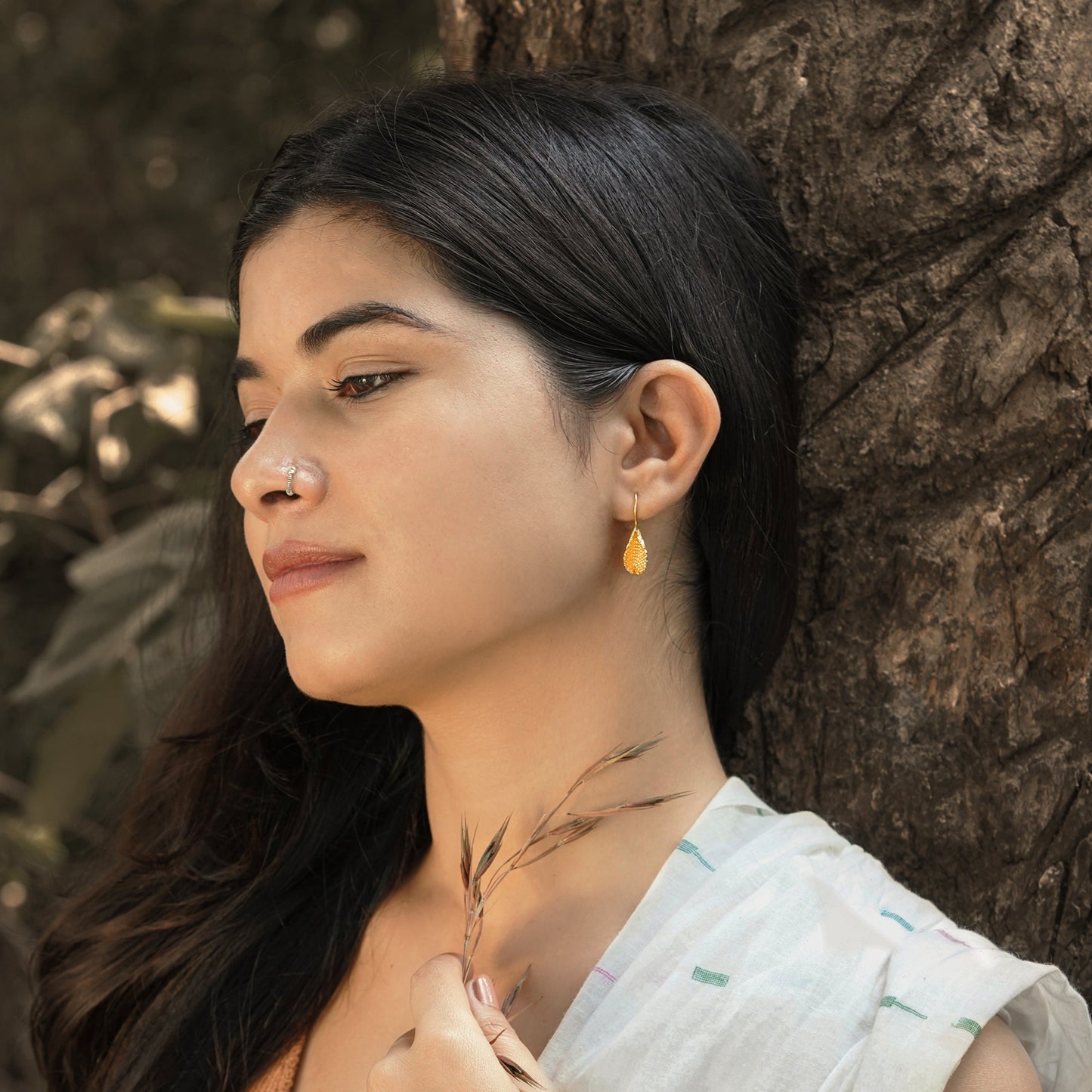 Left front view of woman wearing gold plated beeja Pod earrings.