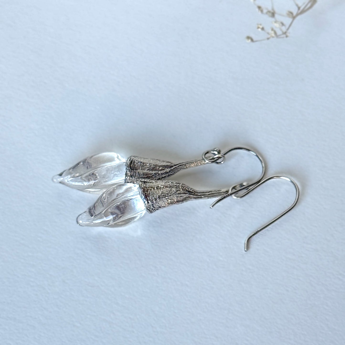 Pair of clear twisted glass bud earrings with silver findings.
