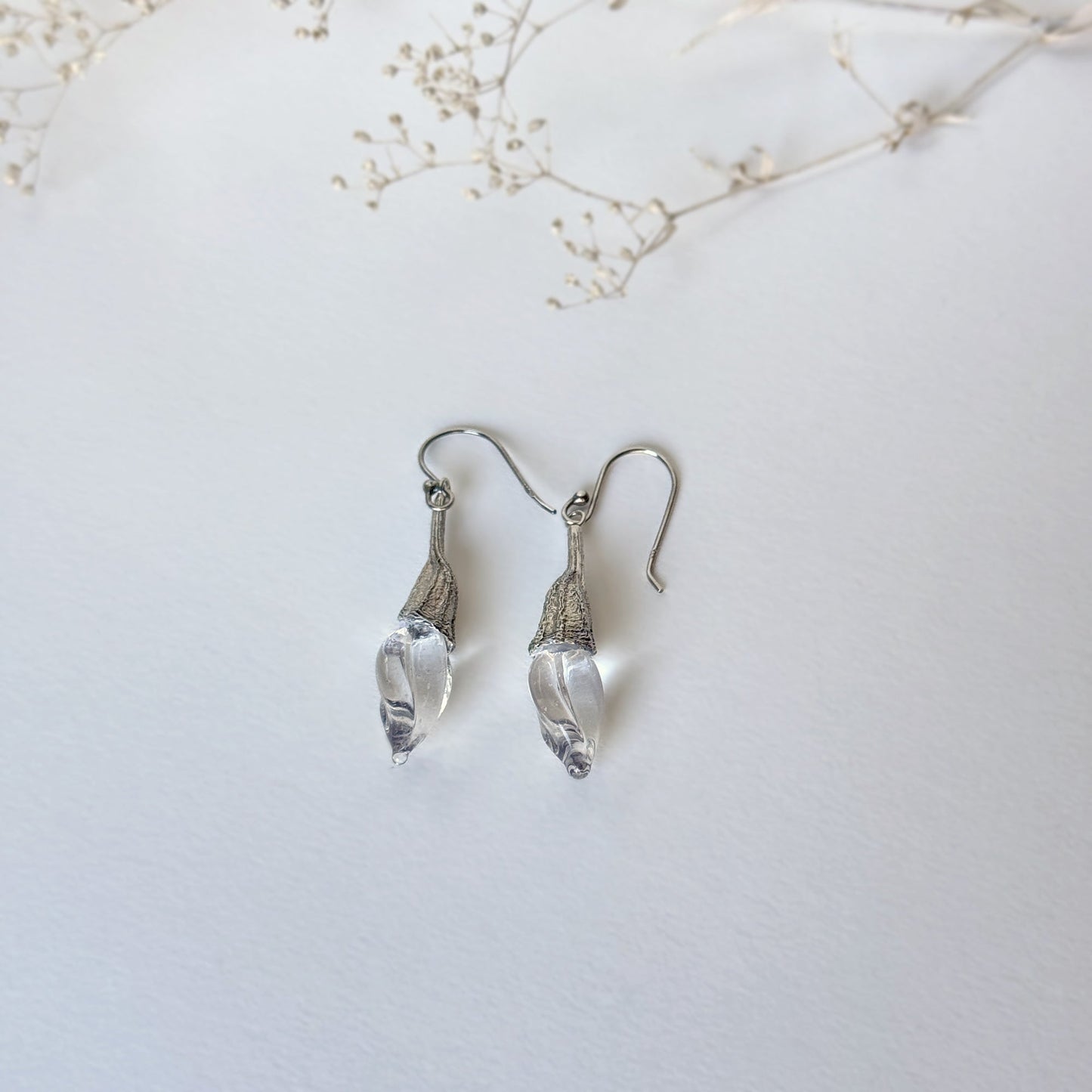 Pair of clear twisted glass bud earrings with silver findings.