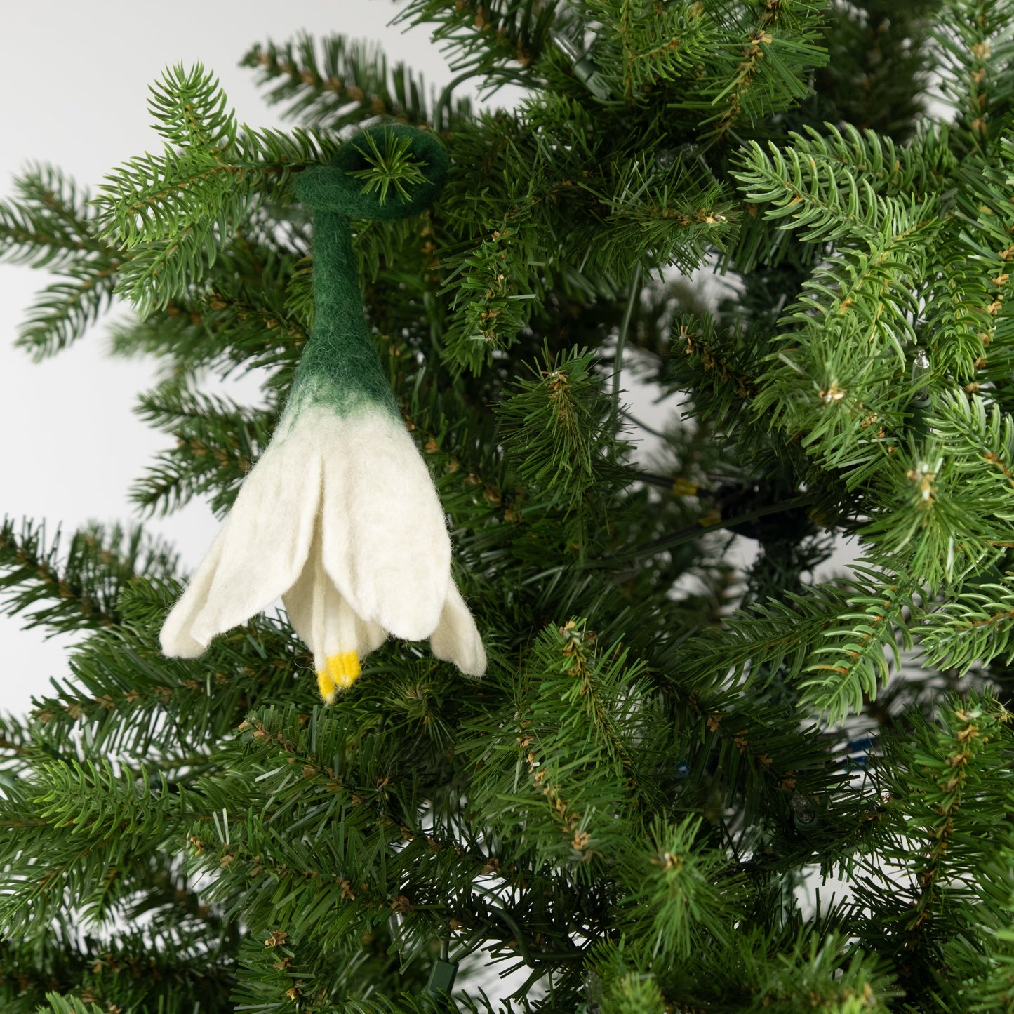 Felt ornament of a white flower on a Christmas tree.