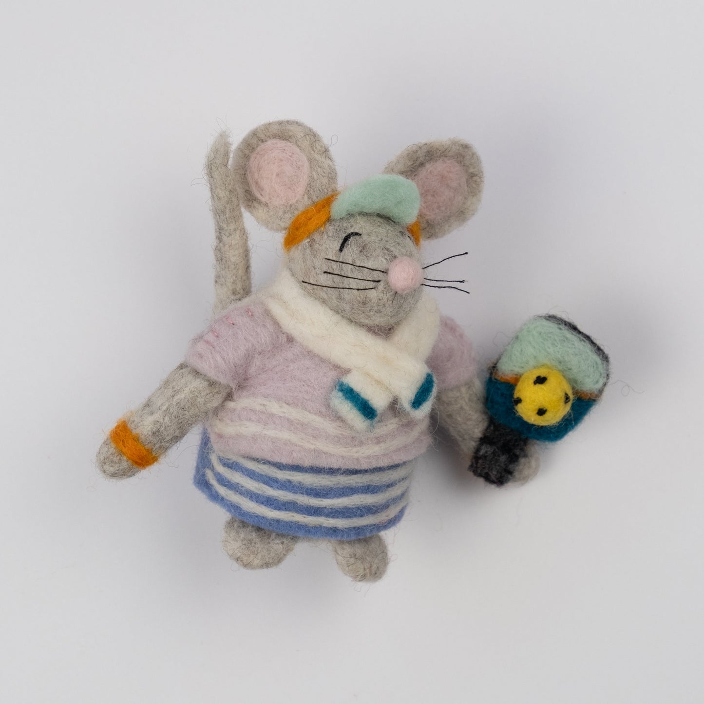 Felted ornament of a mouse dressed in a retro striped sweater, matching skirt, bright orange visor, and tiny sweatbands, with a pickleball paddle and ball in paw.
