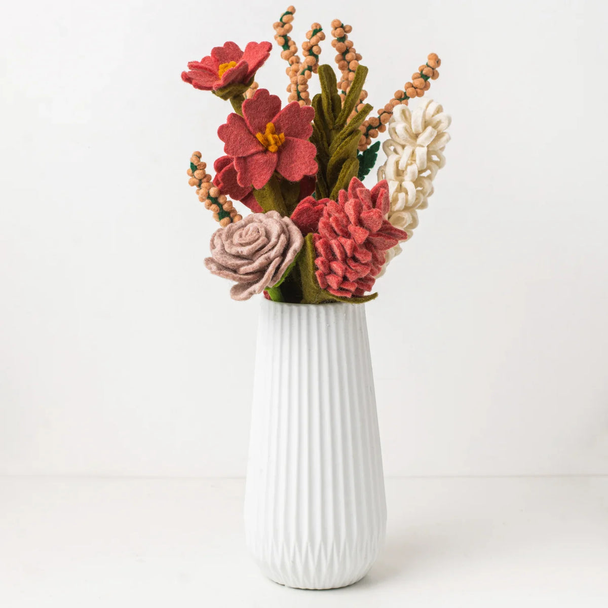 Everlasting felt flower bouquet of various pink and white flowers in a white vase.