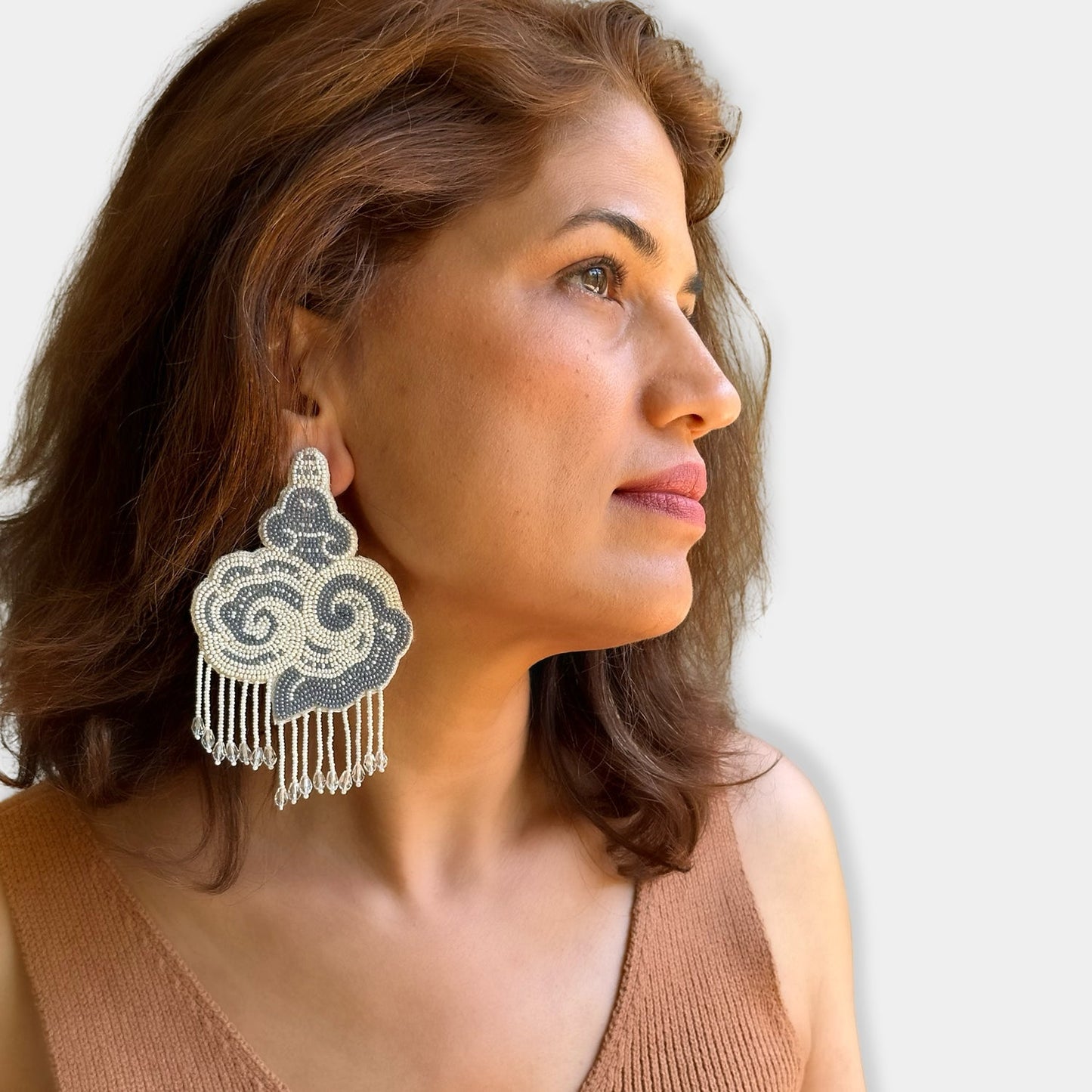 Right front view of woman wearing white and black cloud earrings with tassels.