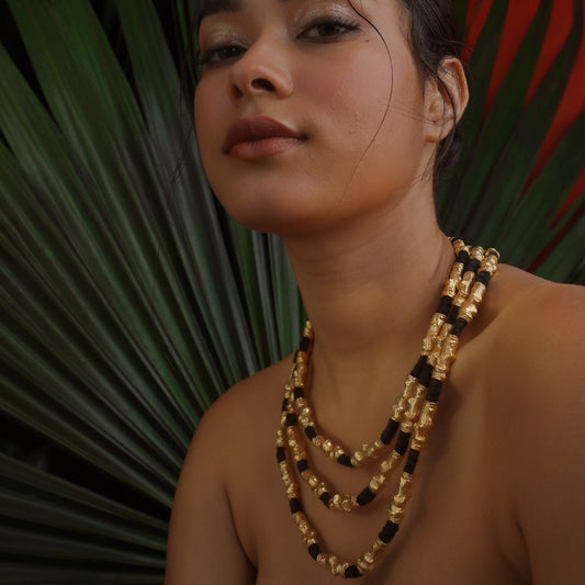 Woman wearing stacked gold plated and black thread necklace