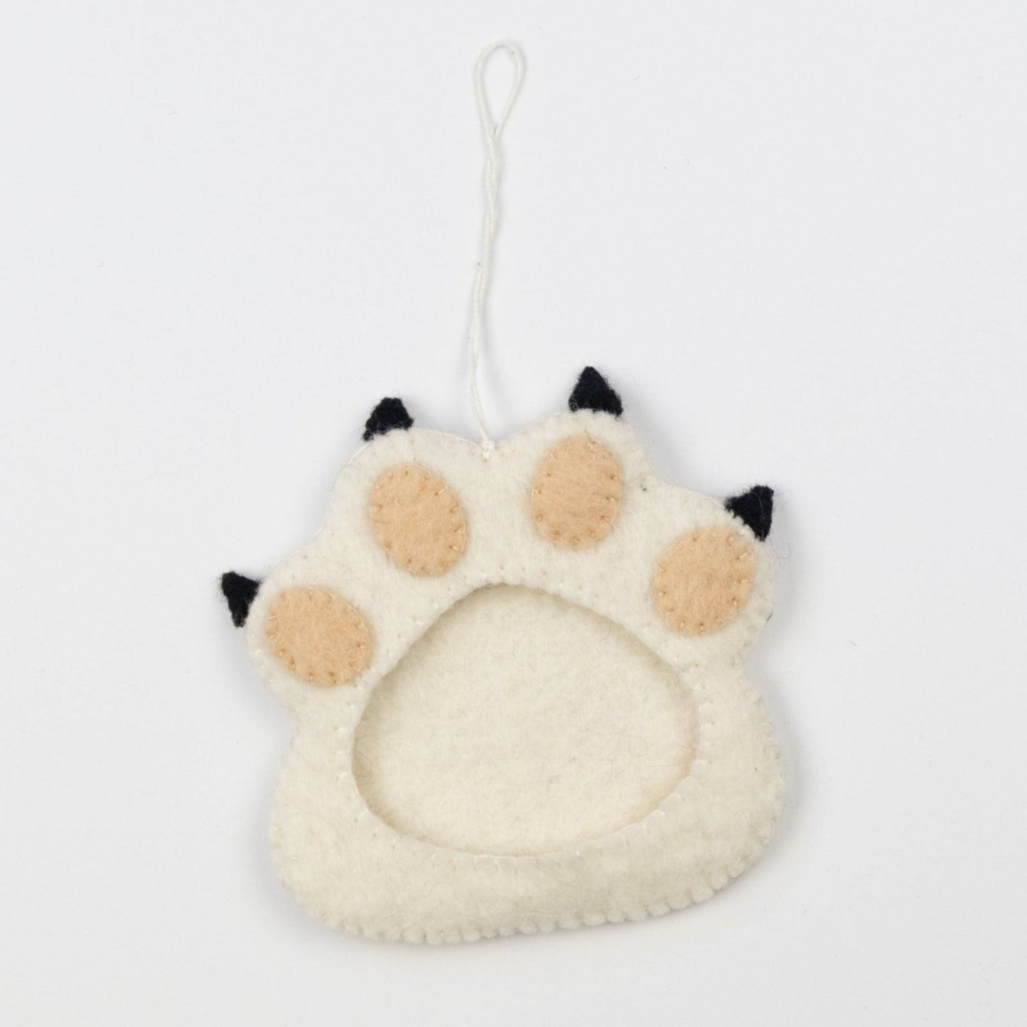 Felt ornament of a white paw print with a picture frame in the middle.