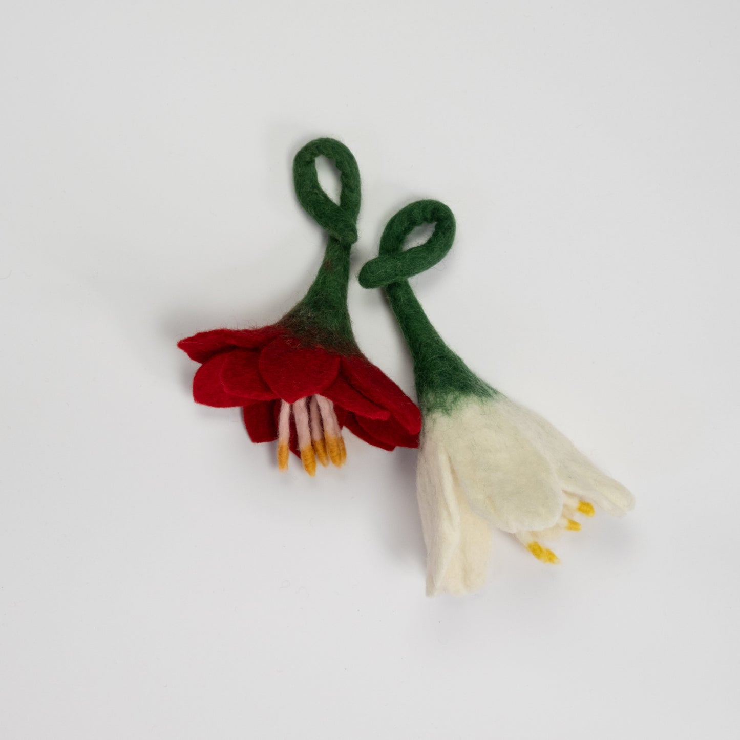 Felt ornaments of a red flower and a white flower.