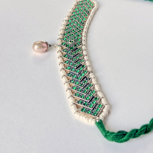 Green and silver choker necklace surrounded by white beads, with a drop pearl at the center.