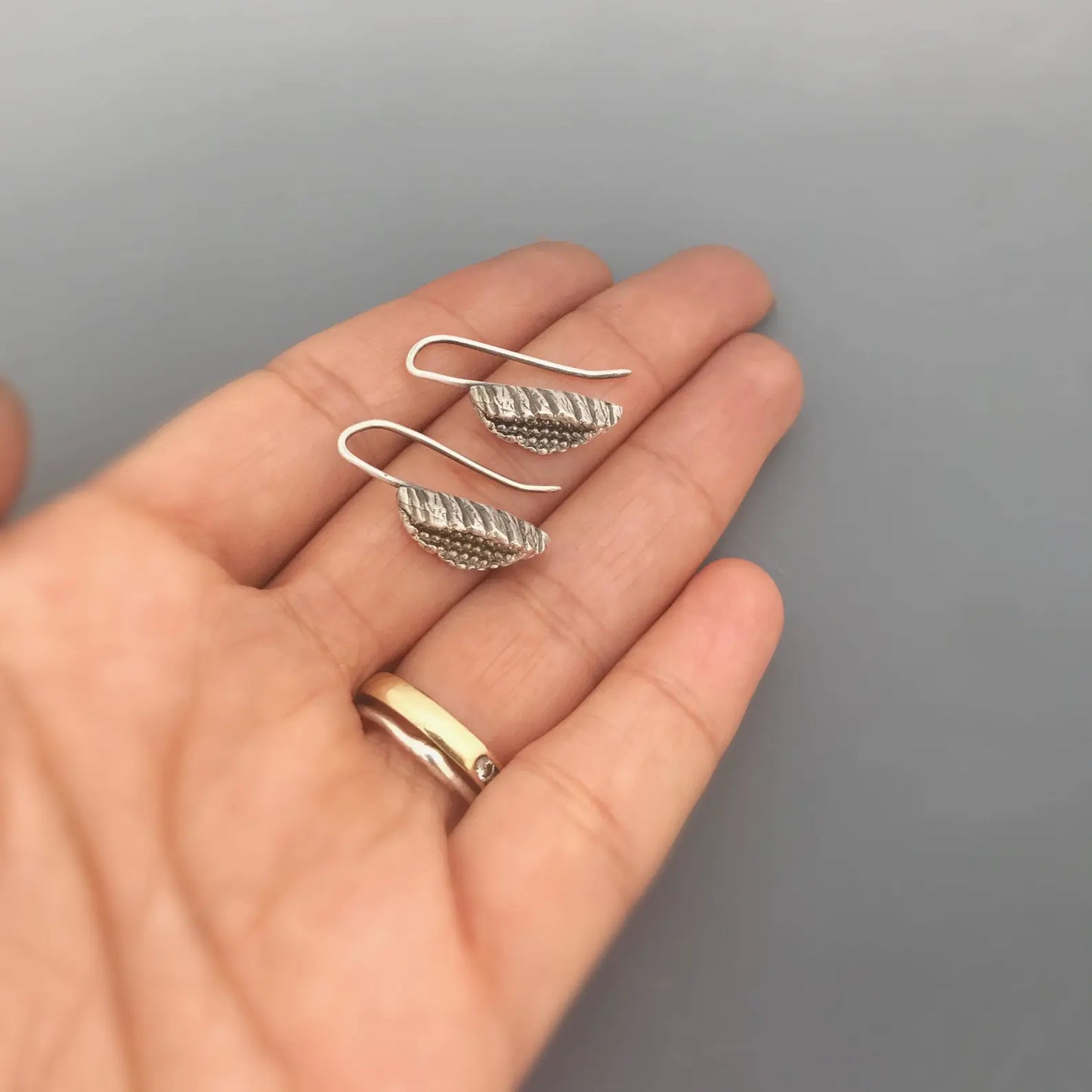 Silver beeja Pod earrings on palm of woman's hand.