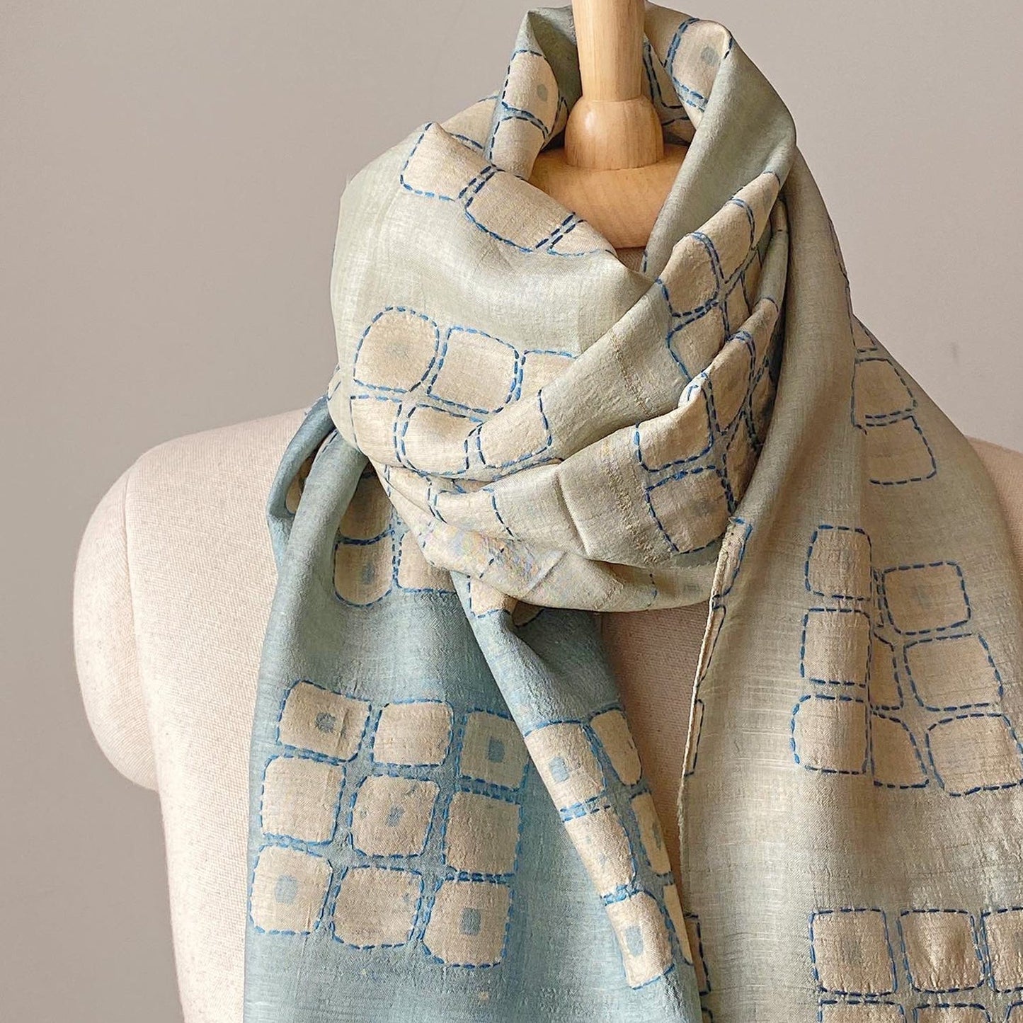 Graduated ombre silk scarf with geometric design wrapped around neck of mannikin.