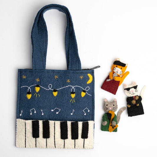 Felt Jazz Cats Puppet Bag features three finger puppets: a singing cat with a beret, a drummer cat with sunglasses, and a saxophone-playing cat. The bag itself has piano keys, string lights, stars, and a glowing moon.
