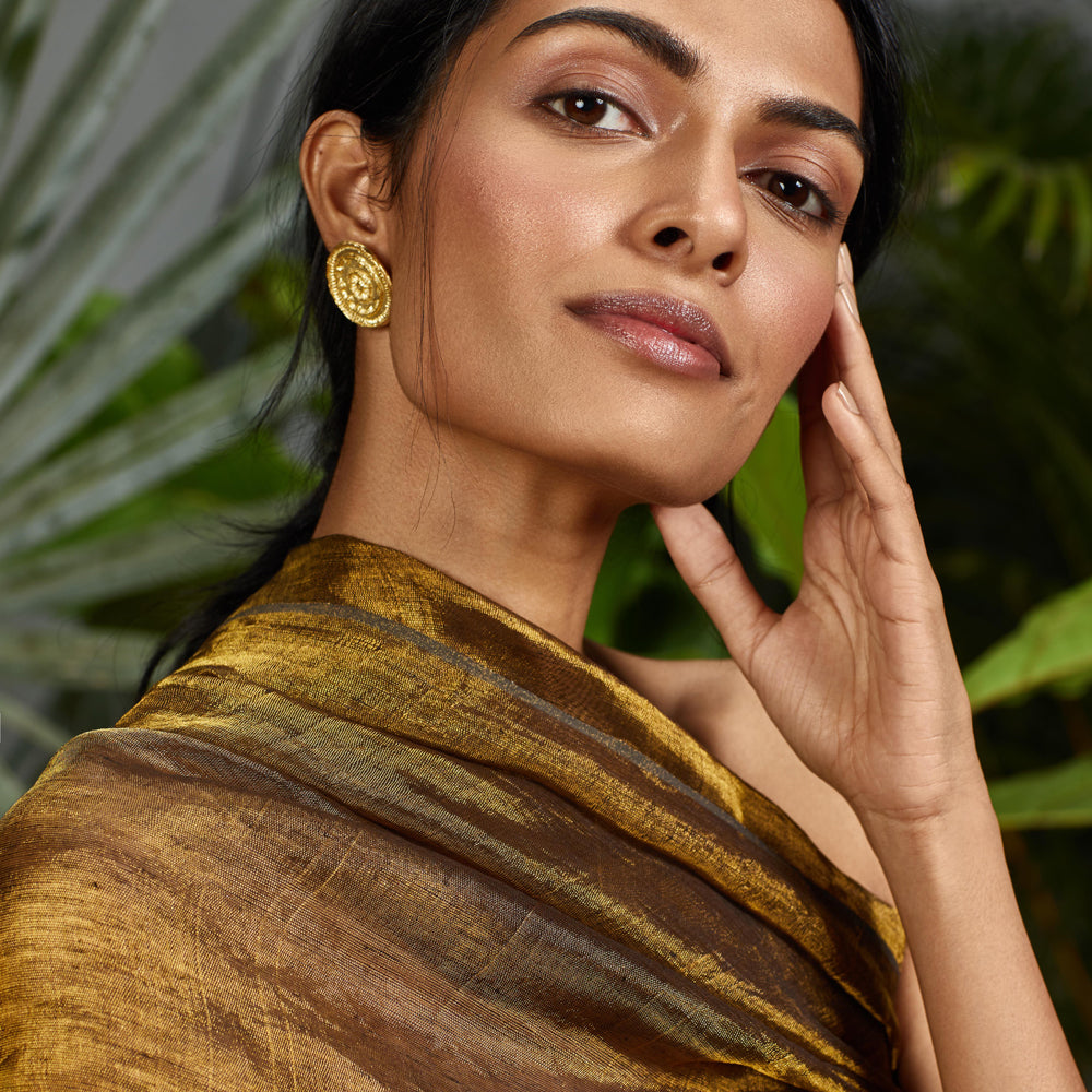 Front view of woman wearing gold mandala earrings.