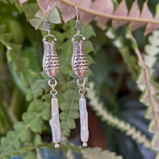 Silver and pearl dangle earings with fish motif hanging on branch.