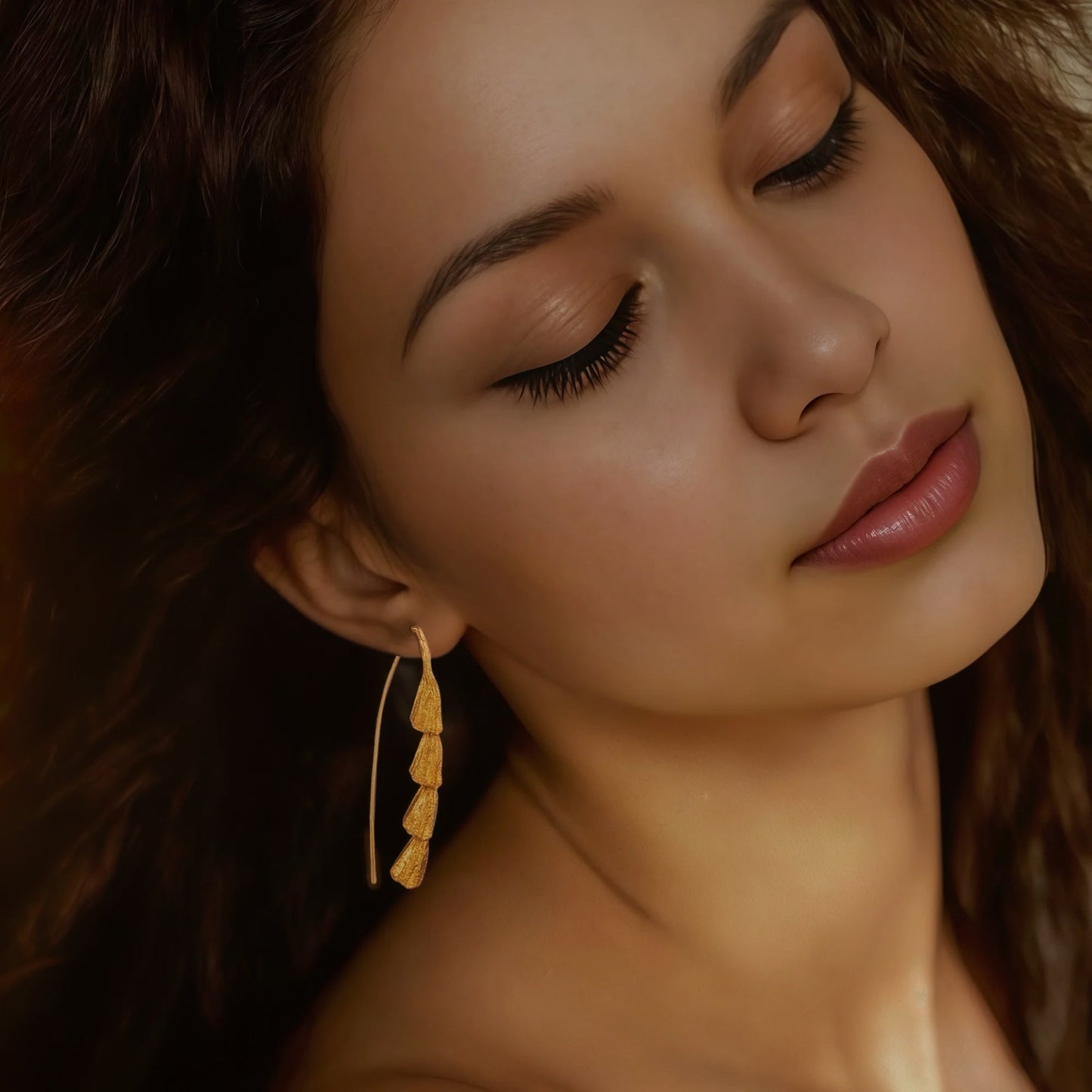 Front view of woman wearing gold plated dangle earrings.