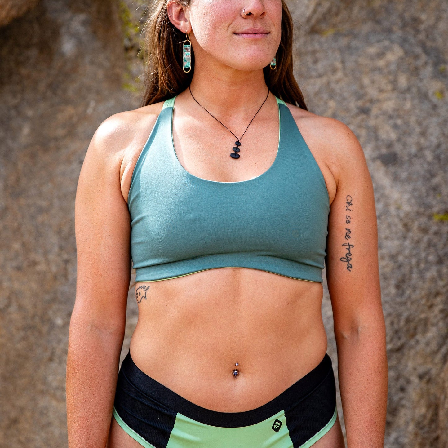 Cropped picture of woman smiling while wearing high- cut toura sports bra in green.