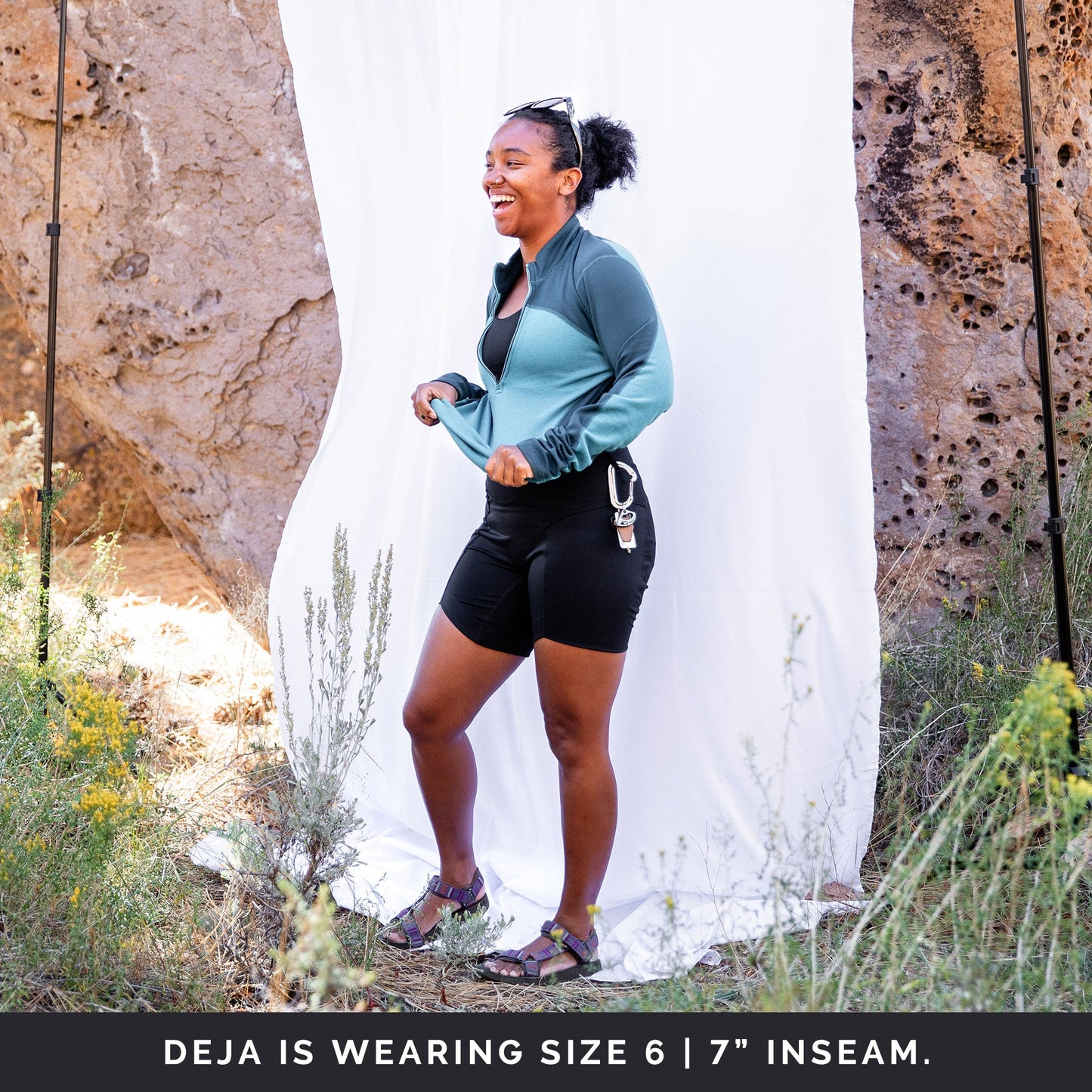 Side view of woman in front of a white sheet, wearing black toura short with 7" inseam.